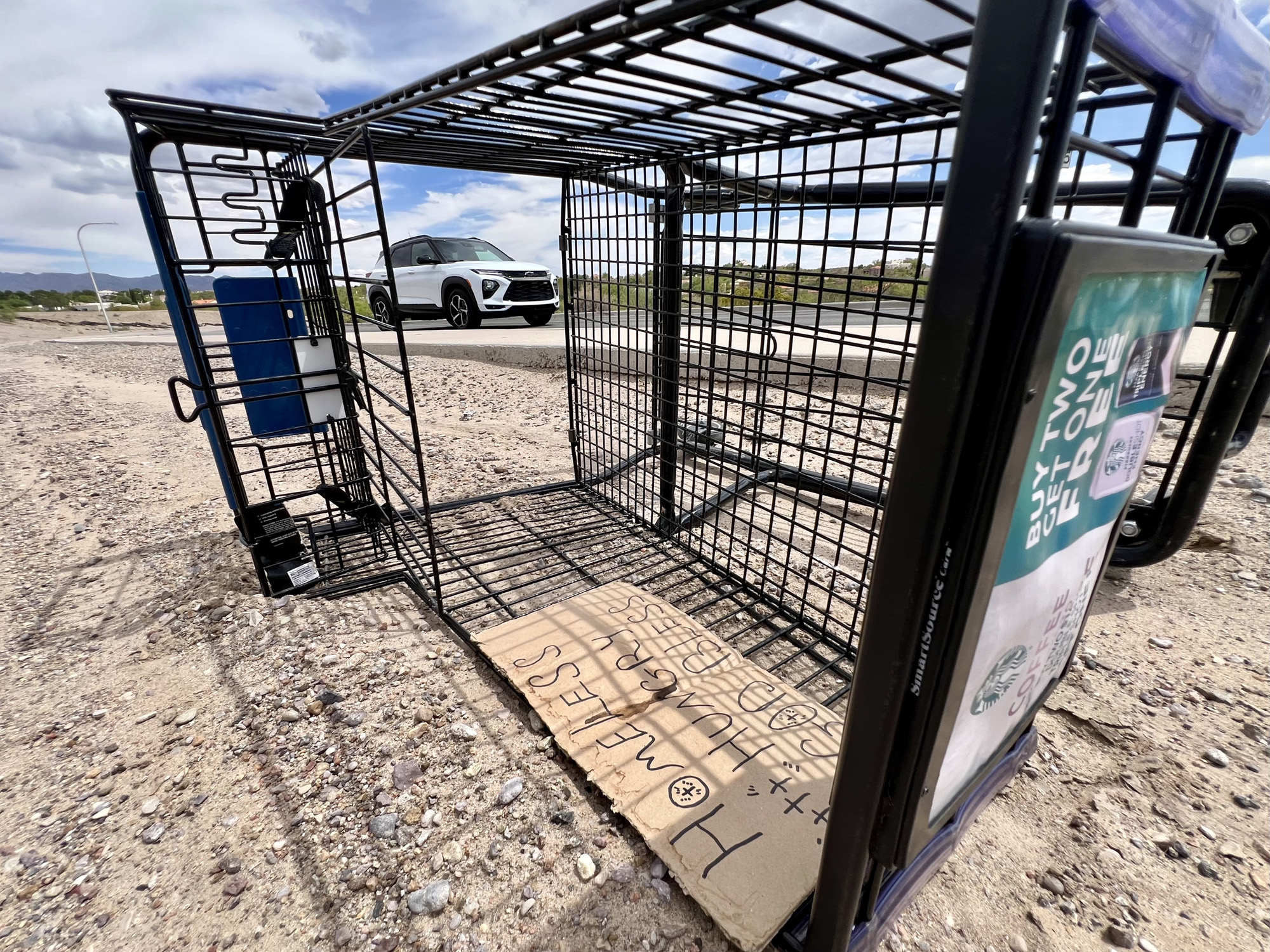 A shopping cart lay on its side near Lohman Avenue on the same day the Las Cruces City Council enacted an ordinance aimed at cracking down on shopping cart use by unhoused people. A cardboard sign in the cart included the words “Homeless,” “hungry” and “God bless,” in addition to a drawing of three crosses. (Photo by Heath Haussamen)