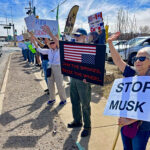 Protesters wave to a supportive motorist during Saturday's demonstration against Elon Musk's actions.